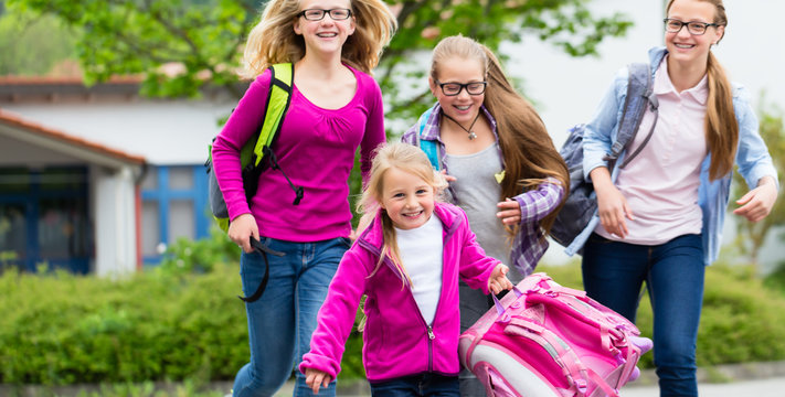 Sch&uuml;ler vor Schule laufen in die Schulpause