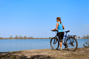 Young woman mountain bike stands on the bank of river