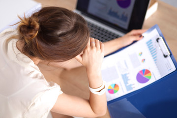 Portrait of tired young business woman with laptop computer at