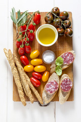 Italian snack lunch. Black Sicilian tomatoes, salami, bread in t