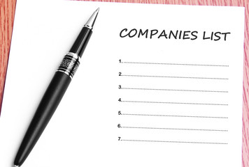 Pen  and notes paper with companies list