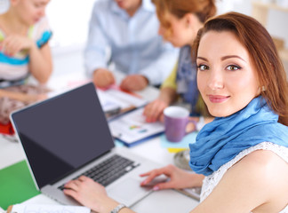 Portrait of attractive female  designer sitting on desk  in