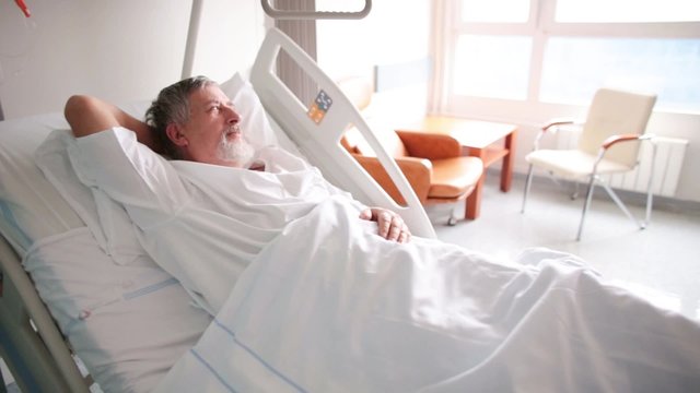 Patient at a hospital, lying on a bed in his room, resting and sleeping, doing much better after the surgery