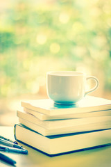 selective focus of white coffee cup and  books stacking 