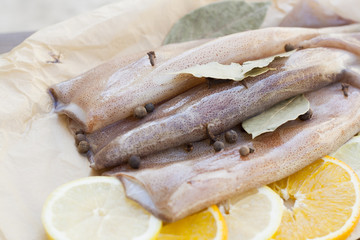 Fresh squid carcass with spices on paper on the wooden table, selective focus