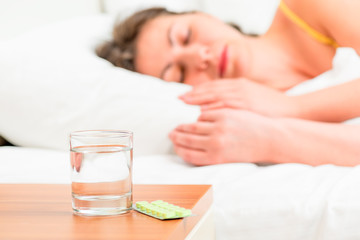 Asleep unhealthy woman and pills on the nightstand