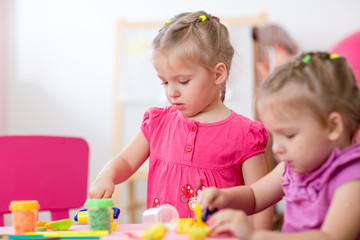 Obraz na płótnie Canvas Little girls learning to work colorful play dough in nursery at