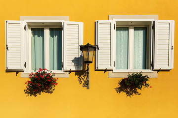 Fototapeta na wymiar Mediteraneean window on orange building with flowers
