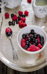 Summer berries in white cup on old metal tray.