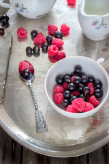 Summer berries in white cup on old metal tray.