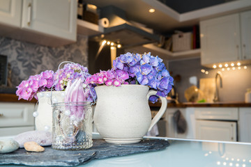 Earthen cup with hydrangea with blurres kitchen in background