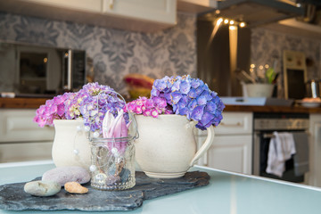 Earthen cup with hydrangea with blurres kitchen in background
