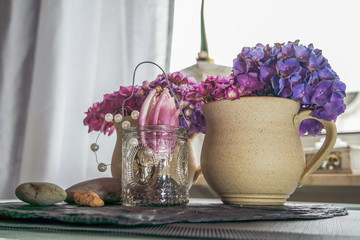 Earthen cup with hydrangea with blurres kitchen in background