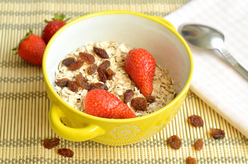 Bowl of oatmeal with raisins and strawberries