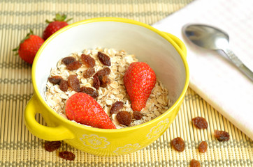 Bowl of oatmeal with raisins and strawberries
