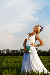 Fototapeta na wymiar Beautiful bride blond blue eyes green field
