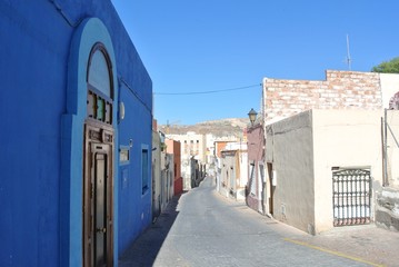 Typical narrow street with sunwashed white and blue facades in the Andalusian seaside resort Almeria, on a sunny summer morning.