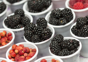 Mulberry and raspberries in white cups