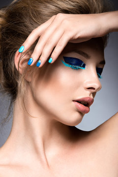 Beautiful girl with bright creative fashion makeup and blue nail polish. Art beauty design.
