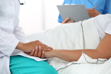 Friendly female doctor's hands holding patient's hand