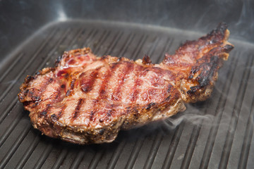 frying beef steak on a ribbed grill pan