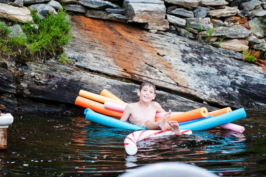 child in a lake in Muskoka region ontario canda floating on pool noodles
