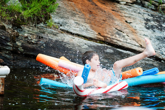 child in a lake in Muskoka region ontario canda floating on pool noodles