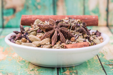 Mix herbs and spices in white bowl over aged wooden background