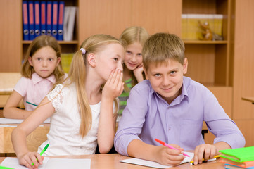 Fototapeta na wymiar girl whispering secrets of the boy in the classroom
