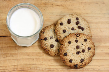 snack: glass of milk and chocolate chip cookies on wooden background

