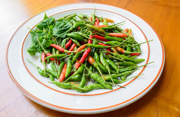 Green, red chili peppers on white dish