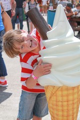 Young boy licking an oversized plastic ice cream