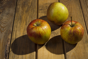 The apples lying on the wooden background.