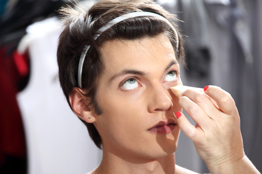 makeup artist applying foundation with a sponge, man in the dres