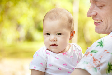 Cute happy baby laughing with his father  having fun outdoors in