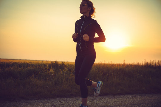 Female Jogging At Sunset.