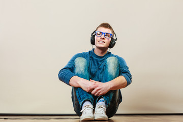 Young man with headphones sitting on floor