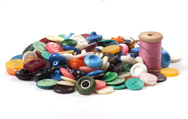 Pile of old colored buttons with thread and needle on white back