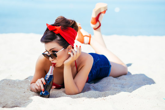 Pin-up on sand with drink