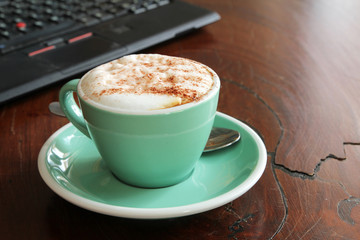 Cup of cappucino coffee with laptop
