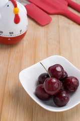 Red Cherries with Red Kitchen Utensils on Wood Background