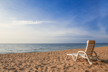 white chair on sand beach with sunshine light