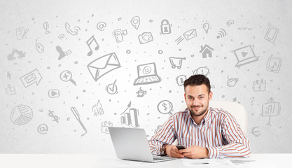 Business man  sitting at table with hand drawn media icons