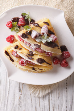 raspberry crepes with chocolate and mint closeup. vertical top view
