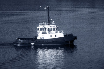 Tug boat with white superstructure underway, side view, monochro