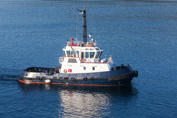 Tug boat with white superstructure and dark blue hull