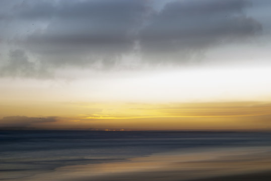 long exposure photo with the camera panned from left to right to make a blurry sunset beach scene