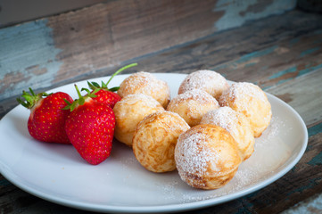 Traditional Dutch poffertjes, mini pancakes, dusted with icing sugar and served with fresh strawberries.