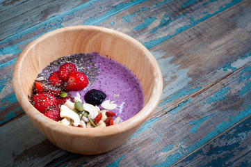 Healthy breakfast fruit smoothie bowl of blueberry and strawberry blended with kefir yogurt and topped with fresh strawberry, chia seeds, goji berries, cashews and pumpkin seeds.