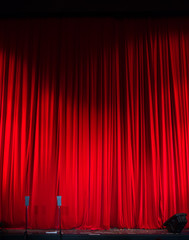 Red closed curtain with light spots in a theater